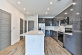 Located on Ivan Allen Jr Blvd NW in Atlanta, GA, this single-floor unit presents a contemporary design with a thoughtful layout and high-quality finishes throughout. The open-concept kitchen is a standout feature, outfitted with sleek, high-gloss dark gray cabinetry extending to the ceiling, stainless steel appliances including a refrigerator, range, microwave, and dishwasher, and a crisp white quartz countertop island that anchors the space. A white subway tile backsplash adds a clean, modern contrast to the cabinetry. Wood-look luxury vinyl plank flooring runs throughout the kitchen and living areas, lending warmth and cohesion.

The living area is bright and open, benefiting from a large sliding glass door that leads to a private balcony offering views of the surrounding Atlanta cityscape. The bedroom is carpeted for comfort and features a ceiling fan, panel-style doors, and its own sliding glass door with direct balcony access and city views. The bathroom is well-appointed with a dark wood vanity, white quartz countertop, undermount sink with brushed nickel fixtures, wood-look flooring, and a glass-enclosed walk-in shower. The overall aesthetic is clean, modern, and move-in ready.