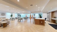 Located at 1642 E Florence Ave in Los Angeles, CA, this single-floor community space offers a generously sized, thoughtfully designed environment ideal for gathering, lounging, and socializing. The space features herringbone-patterned light wood flooring throughout, tying together each distinct zone with a warm, cohesive aesthetic.

The kitchen is outfitted with floor-to-ceiling wood cabinetry, a striking teal geometric tile backsplash, a large center island with a white quartz countertop and bar seating with gold-accented stools, and a stainless steel French-door refrigerator — combining style with full functionality.

The living area showcases vibrant teal accent walls, built-in wood shelving flanking a wall-mounted TV, and colorful original artwork. Rounded architectural columns with warm terracotta bases add a distinctive design touch, while plush neutral seating arrangements invite relaxed lounging.

A bright, open dining and activity area features multiple seating arrangements, abundant overhead lighting, frosted glass partitions along the walls, and a ping-pong table, creating a lively multipurpose zone. A welcoming entryway with glass doors, curated greenery, and accent seating provides a polished first impression. Recessed and flush-mount lighting throughout ensures the entire space remains well-lit and inviting.
