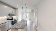 Located at 3550 N A W Grimes Blvd in Round Rock, TX, this well-designed one-bedroom, one-bathroom unit offers a thoughtful single-level layout that maximizes every square foot. The open-concept kitchen is a standout feature, outfitted with granite countertops, white shaker-style cabinetry with matte black hardware, and a full suite of stainless steel appliances including a refrigerator, dishwasher, electric range, and microwave. A large kitchen island with matching granite provides additional prep space and flows naturally into the dining area, which is illuminated by stylish pendant lighting. Light hardwood flooring runs throughout the main living areas, adding warmth and continuity to the space. Sliding glass doors in the dining area open to a private balcony, allowing natural light to pour in and offering views of the surrounding community. The bedroom is a comfortable retreat, carpeted for added coziness, with a large window dressed in blinds that bring in ample natural light. The full bathroom features granite countertops, white cabinetry with black hardware, an undermount sink, and a tub-shower combination with tile surround. A dedicated closet provides convenient storage. The overall design is clean, modern, and move-in ready.