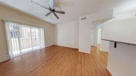 Located at 2400 E Llano Estacado Blvd in Clovis, New Mexico, this single-floor residence offers a clean, well-maintained living environment with a bright and open feel. The main living area is a standout feature, showcasing warm hardwood-style flooring that extends throughout the space, creating a cohesive and inviting atmosphere. A ceiling fan is centrally mounted, adding both functionality and a subtle design element to the room. Large sliding glass doors dressed with vertical blinds lead to a private balcony, allowing generous amounts of natural light to fill the interior. The crisp white walls throughout contribute to a sense of openness and provide a neutral canvas adaptable to a variety of décor styles. A central architectural column adds structural character while helping to define the transition between the living area and the adjacent hallway. The hallway connects to additional rooms, hinting at a thoughtfully laid-out floor plan. Overhead HVAC venting is integrated into the ceiling, ensuring comfort throughout the space. Overall, the residence presents a tidy, move-in-ready environment with practical features and a light-filled, airy ambiance well-suited to everyday living.