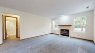 Located on Greenview Circle NW in Canton, Ohio, this single-floor home offers a well-organized layout visible through its open floor plan. The living room serves as a central gathering space, featuring plush gray carpeting, a tile-surround wood-burning fireplace with a warm wood mantel, and two large windows that frame outdoor views and fill the room with natural light. Textured ceilings are consistent throughout the home, adding a classic character to each space.

The kitchen is accessible directly from the main living area and is equipped with warm oak cabinetry, white appliances including a refrigerator, range, and built-in microwave, as well as light wood-look vinyl flooring. A peninsula-style counter provides a transition between the kitchen and the adjoining dining or flex space, which is accented by a chandelier overhead.

The bedroom wing features carpeted rooms with multiple closet options, including a walk-in closet with built-in shelving. A full bathroom offers a framed glass walk-in shower, oak vanity, and light vinyl flooring. The dedicated laundry room includes washer and dryer hookups, wire shelving, and a Concord furnace unit. The attached two-car garage provides ample storage and interior access.