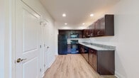 This two-floor residence offers a thoughtfully designed layout with a clean, neutral aesthetic throughout. The kitchen serves as a functional centerpiece, featuring rich dark-espresso cabinetry extending to the ceiling for ample storage, light granite countertops, and a full suite of black appliances including a refrigerator, electric range, microwave, and dishwasher. Light wood-look flooring runs through the kitchen and adjacent areas, adding warmth and easy maintenance underfoot. Recessed lighting illuminates the space evenly overhead.

The bedrooms are finished with wall-to-wall neutral carpeting, creating a comfortable, quiet atmosphere. At least one bedroom includes a closet and a window that invites natural light and outdoor views. An additional carpeted room offers flexible use as a living area or bedroom, with its own access to a walk-in closet. The bathroom features tile flooring, a dark-toned vanity with a white countertop, and a well-lit mirror. Crisp white walls and trim are consistent throughout, contributing to a clean, cohesive interior. The upper floor includes a carpeted hallway connecting the rooms, enhancing the overall sense of a well-organized, multi-level living space.