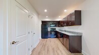 This two-floor residence offers a thoughtfully designed layout with a clean, neutral aesthetic throughout. The kitchen serves as a functional centerpiece, featuring rich dark-espresso cabinetry extending to the ceiling for ample storage, light granite countertops, and a full suite of black appliances including a refrigerator, electric range, microwave, and dishwasher. Light wood-look flooring runs through the kitchen and adjacent areas, adding warmth and easy maintenance underfoot. Recessed lighting illuminates the space evenly overhead.

The bedrooms are finished with wall-to-wall neutral carpeting, creating a comfortable, quiet atmosphere. At least one bedroom includes a closet and a window that invites natural light and outdoor views. An additional carpeted room offers flexible use as a living area or bedroom, with its own access to a walk-in closet. The bathroom features tile flooring, a dark-toned vanity with a white countertop, and a well-lit mirror. Crisp white walls and trim are consistent throughout, contributing to a clean, cohesive interior. The upper floor includes a carpeted hallway connecting the rooms, enhancing the overall sense of a well-organized, multi-level living space.