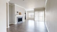This single-story, 4-bedroom, 3-bathroom home offers a thoughtfully designed layout that balances comfort and functionality. The open-concept living and kitchen area serves as the heart of the home, anchored by a striking fireplace with a marble-tiled surround and a classic white mantel. Wide-plank hardwood-style flooring extends throughout the main living spaces, complemented by crown molding that adds an elegant finishing touch. Large sliding glass doors and windows flood the living area with natural light and provide access to the outdoors.

The kitchen is well-equipped with rich, dark espresso cabinetry, granite countertops, a white subway tile backsplash, and stainless steel appliances, including a range, microwave, and refrigerator. The layout offers generous counter space and storage throughout.

The primary bedroom is a comfortable retreat, featuring plush carpeting, a ceiling fan, a walk-in closet, and a private exterior door. The remaining three bedrooms also feature carpet and share access to well-appointed bathrooms. Each bathroom is finished with granite-topped dark wood vanities, hardwood-style flooring, and tub/shower combinations. Two closets and two hallways contribute to the home's efficient and practical floor plan.