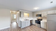 Located at 304 Fort Town Rd in Fort Oglethorpe, Georgia, this two-bedroom, one-bathroom single-story home offers a practical and well-designed layout. The kitchen is a standout feature, finished with light gray cabinetry, white countertops, and a full suite of stainless steel appliances including a range, microwave, dishwasher, and refrigerator. Light wood-look flooring runs throughout the main living and kitchen areas, lending a clean, cohesive aesthetic. Natural light filters in through blinds-covered windows, brightening the open feel of the space. Both bedrooms are comfortably sized, carpeted for warmth underfoot, and each equipped with a ceiling fan with light fixture. The primary bedroom offers a generous footprint ideal for standard bedroom furnishings. The full bathroom features tile flooring, a combined tub and shower, a toilet, and a vanity with gray cabinetry consistent with the kitchen's design. Additional spaces include a utility room and a closet, providing practical storage solutions. The neutral color palette throughout creates a calm and versatile backdrop, making the home easy to personalize. The overall layout, as seen in the dollhouse view, is efficient and well-organized, maximizing the use of space on a single floor.