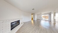 Located at 1201 N Rainbow Blvd in Las Vegas, NV, this single-floor, one-bedroom, one-bathroom home offers a well-organized and efficiently designed layout. Light wood-style flooring flows consistently throughout, lending a clean, cohesive look to every room.

The spacious living room is a standout feature, anchored by a classic white brick fireplace and flooded with natural light from a sliding glass door that opens to a private patio. Adjacent to the living room, the combined dining room and kitchen presents a galley-style layout with ample gray cabinetry, white countertops, white appliances, and a window that brings in additional natural light.

The bedroom is a comfortable, well-lit space featuring a ceiling fan, a window with views of surrounding greenery, and access to multiple closets, including a generous walk-in with double hanging rods. The full bathroom includes a tub-shower combination with chrome fixtures, a vanity with a sink, and a large mirror with overhead lighting.

Additional spaces include a versatile den, a hallway connecting the main areas, and an attached garage with a concrete floor and exposed wood-beam ceiling. The patio provides a welcoming outdoor retreat. Throughout, the home's bright white walls and consistent flooring create a light, airy, and move-in-ready atmosphere.