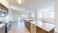 This single-floor, 3-bedroom, 2-bathroom residence offers a thoughtfully designed open-concept layout that maximizes functionality and livability. The kitchen serves as the heart of the home, anchored by a generous island with striking granite-style countertops and an undermount sink. Dark wood cabinetry provides ample storage, while a full suite of stainless steel appliances — including a refrigerator, range, microwave, and dishwasher — completes the space with a modern, cohesive look. The kitchen flows seamlessly into the living area, which is bathed in natural light from multiple windows and a glass-panel door that leads to the outdoors. Light-toned wood-style flooring runs throughout, lending warmth and continuity to the entire residence. The three bedrooms are bright and well-proportioned, each featuring windows with exterior views. The spacious primary bedroom offers a comfortable and private retreat. Both bathrooms are clean and functional, each featuring a tub/shower combination with a white surround, wood-style flooring, and dark wood vanity cabinetry. A dedicated closet provides convenient additional storage. The overall aesthetic is modern and neutral, offering a versatile canvas well-suited to a variety of furnishing styles.