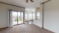 This single-floor residence offers a thoughtfully designed open layout that maximizes both comfort and functionality. The main living area is generously sized, featuring plush wall-to-wall carpeting, neutral tones throughout, and a ceiling fan overhead. Large sliding glass doors open directly onto a private balcony, flooding the space with natural light and providing outdoor views of the surrounding neighborhood. The adjoining dining and kitchen pass-through area creates a seamless flow between spaces.

The kitchen is well-equipped with rich warm-toned wood cabinetry, granite-style countertops, a classic white subway tile backsplash, and a full suite of stainless steel appliances including a refrigerator, range, microwave, and dishwasher. Dark hardwood-style flooring runs throughout the kitchen and hallways, providing a clean contrast to the carpeted living and bedroom areas.

The bedrooms are comfortably sized, each featuring soft carpeting, bright windows with slatted blinds, and ample wall space. The bathrooms are finished with matching warm wood vanities, granite-style countertops, large framed mirrors, and hardwood-style flooring, lending a cohesive and polished aesthetic. A hallway connects all areas efficiently, completing this functional and inviting living space.