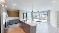Located in Smyrna, GA, this well-appointed 3-bedroom, 2-bathroom residence offers a thoughtfully designed single-floor layout with modern finishes throughout. The open-concept kitchen serves as the heart of the home, showcasing a large center island with a quartz countertop and undermount sink, pendant lighting, two-tone cabinetry in warm wood and slate gray, a white subway tile backsplash, and stainless steel appliances. Floor-to-ceiling windows flood the living area with abundant natural light and provide sweeping outdoor views, while a ceiling fan adds comfort to the space. A private balcony extends the living area outdoors. The bedrooms are carpeted and bright, each featuring ceiling fans and generous windows with exterior views. The primary bedroom includes a well-organized walk-in closet with built-in wire shelving. Both bathrooms are finished with dark cabinetry, white countertops, and light wood-style flooring; one features a soaking tub with tiled surround. Practical amenities include a dedicated laundry room with side-by-side washer and dryer, a utility room, and three closets for ample storage. Light wood-style flooring runs throughout the main living areas, tying the home's contemporary aesthetic together cohesively.