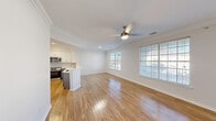 Located in Austin, TX, this two-story, two-bedroom, three-bathroom home offers a well-designed layout spread across two floors. The main level features an open-concept kitchen and living area filled with natural light from large windows. The living room is outfitted with hardwood-style flooring, crown molding, and a ceiling fan, creating a bright and comfortable gathering space. The kitchen is a standout, showcasing two-tone cabinetry — white upper cabinets paired with gray lower cabinets — accented by gold hardware, a tiled backsplash, white countertops, and stainless steel appliances including a range and over-the-range microwave. A peninsula provides additional counter space and separates the kitchen from the living area. A carpeted staircase with a white handrail leads to the upper floor, which houses both bedrooms and additional bathrooms. The spacious primary bedroom features hardwood-style flooring, crown molding, a ceiling fan, and multiple windows allowing ample natural light. The second bedroom also features the same flooring and window treatments. The bathrooms are clean and functional, featuring white tile, a tub-shower combo, and brushed nickel fixtures. A dedicated closet and hallway complete the upper level, rounding out this efficient and well-appointed Austin home.
