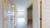 This single-floor unit presents a thoughtfully designed layout with a cohesive modern aesthetic carried throughout each space. The kitchen serves as a standout feature, showcasing dark, textured flat-front cabinetry extending from floor to ceiling, complemented by a light grey subway tile backsplash and crisp white countertops. Stainless steel appliances, including a side-by-side refrigerator with water dispenser, electric range, built-in microwave, and dishwasher, provide a fully equipped cooking environment. Light wood-style flooring runs continuously through the kitchen and into the open living area, which benefits from multiple large windows fitted with horizontal blinds that allow ample natural light to fill the space.

The hallway connects the living areas to the private spaces, featuring decorative paneled doors with gold-toned hardware alongside louvered closet doors. A carpeted walk-in closet offers generous storage. The bathroom is finished with wood-look tile flooring, a dark vanity with white countertop, and a full tub-shower combination with white tile surround. Throughout the unit, neutral wall tones and clean lines create a bright, cohesive, and move-in-ready environment.