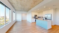 Located at 1801 Patterson Street in Nashville, TN, this contemporary 2-bedroom, 2-bathroom residence offers a thoughtfully designed single-level layout with striking architectural character. The open-concept living, dining, and kitchen area serves as the heart of the home, featuring light hardwood flooring, exposed concrete ceilings, and an abundance of natural light streaming through large windows that frame panoramic views of the Nashville skyline and surrounding cityscape.

The kitchen is outfitted with sleek white flat-front cabinetry, light quartz countertops, a horizontal tile backsplash, and a full suite of stainless steel appliances including a French door refrigerator, electric range, and built-in microwave. A central island with an undermount sink and matte black faucet provides additional workspace and casual seating.

Both bedrooms are generously proportioned with the same light hardwood flooring and exposed concrete ceilings. The primary bedroom benefits from expansive corner windows offering sweeping elevated city views and access to a private balcony. Ample closet space is provided throughout, with three closets in total across the unit.

The bathrooms are finished in a clean, modern style featuring white tilework, glass-enclosed showers, and contemporary vanities. A dedicated laundry area and utility room add practical convenience to this well-appointed Nashville residence.