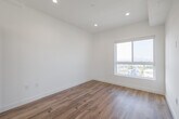 Located at 5801 W Pico Blvd in the heart of Los Angeles, this contemporary single-floor unit offers a thoughtfully designed open-concept layout with clean lines and a bright, modern aesthetic throughout. Warm hardwood-style flooring flows seamlessly across the main living areas, complementing the crisp white walls and recessed lighting overhead.

The kitchen is a standout feature, outfitted with sleek two-tone cabinetry in taupe and gray, a white tile backsplash, light countertops, and a full suite of stainless steel appliances including a gas range, built-in microwave, dishwasher, and a side-by-side refrigerator. An in-unit stacked washer and dryer is conveniently tucked nearby.

The living area is generously proportioned and filled with natural light from large windows, while the bedroom offers direct access to a spacious private balcony through sliding glass doors. From the balcony, residents enjoy open views of the Los Angeles skyline and surrounding neighborhood.

The bathroom is cleanly finished with neutral tile flooring, a pedestal sink, a wall-mounted mirror, and a tiled walk-in shower. A separate water closet provides additional privacy. The unit's overall design embraces a minimalist sensibility, making it a versatile and light-filled space in a vibrant LA location.