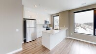 Located at 1425 Block Line in Kitchener, Ontario, this well-appointed 2-bedroom, 2-bathroom unit offers a thoughtfully designed single-floor layout. Warm-toned luxury vinyl plank flooring flows consistently throughout, complemented by neutral greige walls and crisp white trim, creating a clean, cohesive aesthetic.

The modern kitchen is a standout feature, showcasing sleek white cabinetry, light quartz countertops, a central island with an integrated sink, and a full suite of stainless steel appliances. Large black-framed windows draw in generous natural light and offer views of the surrounding Kitchener neighbourhood.

The open-concept dining and living area provides a flexible, spacious feel, with ample room for varied furniture arrangements. Both bedrooms are well-sized, with the primary bedroom benefiting from its own dedicated closet. A second closet adds further storage convenience elsewhere in the unit.

The two bathrooms are finished in a consistent modern style — one featuring a tiled tub-shower combination, and the other a sleek glass-enclosed walk-in shower, both with white vanities and tile flooring. An in-suite laundry area adds everyday practicality. A private balcony extends the living space outdoors, rounding out this functional and stylish urban residence.