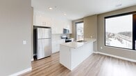 Located at 1425 Block Line in Kitchener, Ontario, this well-appointed 2-bedroom, 2-bathroom unit offers a thoughtfully designed single-floor layout. Warm-toned luxury vinyl plank flooring flows consistently throughout, complemented by neutral greige walls and crisp white trim, creating a clean, cohesive aesthetic.

The modern kitchen is a standout feature, showcasing sleek white cabinetry, light quartz countertops, a central island with an integrated sink, and a full suite of stainless steel appliances. Large black-framed windows draw in generous natural light and offer views of the surrounding Kitchener neighbourhood.

The open-concept dining and living area provides a flexible, spacious feel, with ample room for varied furniture arrangements. Both bedrooms are well-sized, with the primary bedroom benefiting from its own dedicated closet. A second closet adds further storage convenience elsewhere in the unit.

The two bathrooms are finished in a consistent modern style — one featuring a tiled tub-shower combination, and the other a sleek glass-enclosed walk-in shower, both with white vanities and tile flooring. An in-suite laundry area adds everyday practicality. A private balcony extends the living space outdoors, rounding out this functional and stylish urban residence.