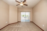 This well-appointed single-floor residence offers a thoughtfully designed layout with a variety of functional and comfortable living spaces. The open living area is a standout feature, showcasing warm hardwood flooring, a ceiling fan, and a tile-surround fireplace set into a recessed niche, flanked by large windows that allow abundant natural light to fill the room. Sliding glass doors lead directly to a private balcony, extending the living space outdoors with pleasant exterior views.

The kitchen is efficiently configured in a U-shaped layout and features rich medium-toned wood cabinetry, laminate countertops, and black appliances including a range, overhead microwave, and refrigerator. A breakfast bar peninsula provides additional counter space and casual dining. Tile flooring runs throughout the kitchen and entry areas, offering durability and easy maintenance.

The carpeted bedrooms are generously sized with ceiling fans and vertical blind-covered sliding doors that provide additional access to outdoor areas. Natural light flows freely into each room, creating a bright and airy atmosphere.

The bathroom includes a single-sink vanity with storage, tile flooring, and is conveniently connected to an in-unit stacked washer and dryer, adding practical day-to-day convenience. Overall, the space presents a clean, functional design with comfortable finishes throughout.