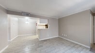 This single-story space offers a cohesive, neutral aesthetic with warm greige walls and light wood-look tile flooring that flows consistently throughout. The open-concept living and dining area is defined by crown molding and connects seamlessly to the kitchen via a peninsula counter, creating an accessible and functional layout. A pendant light fixture illuminates the dining zone, adding a subtle design accent.

The galley-style kitchen is well-equipped with white cabinetry, marble-look countertops, black appliances including a refrigerator, electric range, and dishwasher, along with an under-cabinet range hood. The layout maximizes storage and counter space efficiently within its compact corridor design.

Multiple bedrooms provide comfortable, flexible living spaces, each featuring light wood-look tile flooring, ceiling fans with light kits, and windows with blinds that allow natural light to filter in. Closet access is present in the bedrooms, adding practical storage.

Two bathrooms echo the home's clean aesthetic, each featuring a white vanity with a marble-style countertop, large mirror, and subway tile detailing near the tub and shower areas. The overall ambiance of the space is bright, clean, and move-in ready.