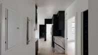Located in the Côte-des-Neiges neighbourhood of Montréal, this thoughtfully designed 3-bedroom, 1-bathroom unit offers a contemporary aesthetic defined by a bold contrast of crisp white walls and striking black accents. Light hardwood flooring flows consistently throughout, lending warmth and cohesion to the entire space.

The kitchen serves as a standout feature, showcasing full-height dark cabinetry, stainless steel appliances including a range, microwave, and dishwasher, and a dramatic white marble-veined backsplash that extends the full width of the cooking wall. The open layout connects the kitchen seamlessly to the rest of the unit.

Each of the three bedrooms is bright and cleanly finished, with black-framed windows that frame views of surrounding greenery and the neighbourhood streetscape. Baseboard heating units are present in each room, and the primary bedroom includes a full-length mirrored closet with a sleek black frame. Black panel interior doors add a refined, modern touch throughout the hallways and rooms.

The bathroom features marble-look tile surfaces, a round mirror, and a glass-enclosed shower, maintaining the unit's consistent modern design language. The overall ambiance is clean, minimal, and move-in ready, making it a functional and stylish home in one of Montréal's well-connected districts.