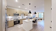 Located at 2005 Empire Street in Charlotte, NC, this thoughtfully designed one-bedroom, one-bathroom residence offers a contemporary living experience with high-end finishes throughout. The open-concept kitchen and living area serves as the heart of the home, featuring light wood cabinetry with matte black hardware, white quartz countertops, stainless steel appliances, and a central island with seating — all illuminated by striking pendant lighting and recessed fixtures. Light-toned hardwood-style flooring flows seamlessly through the main living area, enhancing the bright and airy atmosphere. The living room offers generous space for lounging and entertaining, with natural light streaming in through large windows. The bedroom is a calm retreat, fitted with plush carpet, a ceiling fan, ample natural light from a sizeable window, and access to a well-appointed walk-in closet with built-in shelving. A second closet provides additional storage. The spa-inspired bathroom impresses with marble-style tile, a soaking tub, glass-enclosed shower, dual vanity with illuminated mirrors, and warm wood cabinetry. A private patio with turf and a dedicated laundry area complete this well-rounded residence.