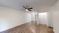 Located at 2701 NW 23rd Blvd in Gainesville, FL, this single-floor unit offers a clean, modern aesthetic throughout its well-appointed layout. The living area features durable wood-style plank flooring, crisp white walls, and a ceiling fan with light fixture. A sliding glass door floods the space with natural light and provides direct access to outdoor greenery, enhancing the open and airy feel of the room. The front entry opens directly into this welcoming living space.

The kitchen is designed for functionality and style, featuring white shaker-style cabinetry, light quartz countertops, and a full suite of stainless steel appliances including a refrigerator, dishwasher, range, and over-the-range microwave. A utility closet with wire shelving is conveniently located adjacent to the kitchen, and a pass-through counter connects the kitchen to the main living area.

The bedrooms are finished with plush carpeting and ceiling fans, offering a comfortable retreat. Multiple closets throughout the unit provide generous storage, including built-in shelving. The bathroom is bright and well-appointed with a white vanity, quartz countertop, large mirror with overhead lighting, and a tub-shower combination. Wood-style flooring continues into the bathroom, tying the space together with a cohesive, updated look.