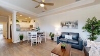 Located at 1300 Mariner Blvd in Spring Hill, FL, this well-appointed single-story home offers 1 bedroom, 2 bathrooms, an office, and a thoughtfully designed open-concept floor plan. The living room is bright and welcoming, featuring a tray ceiling with crown molding, light hardwood-style flooring, plantation shutters, and ample space for comfortable seating arrangements. It flows seamlessly into the dining area, which is framed by a decorative column and opens directly to the kitchen. The kitchen is a standout feature, outfitted with crisp white shaker cabinetry, granite countertops, subway tile backsplash, and stainless steel appliances including a range, microwave, dishwasher, and refrigerator. The primary bedroom is generously sized with a built-in closet and continued hardwood-style flooring. The dedicated office receives excellent natural light through plantation-shuttered windows and includes a glass-paned door for privacy. Both bathrooms are elegantly finished—one features large-format tile, a walk-in shower, and granite vanity, while the other mirrors the same quality craftsmanship with travertine-style tile flooring. Throughout, the home maintains a cohesive coastal aesthetic with neutral tones, clean lines, and refined details.