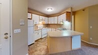 Located at 812 Tenth Ave N in Sartell, Minnesota, this single-floor unit offers a practical and comfortable layout designed for everyday living. The kitchen is a functional highlight, featuring white cabinetry with wood-tone trim accents, generous counter space, a double-basin sink, a built-in electric range, and a peninsula that adds additional workspace and defines the transition into the living area. Durable tile-style flooring anchors the kitchen, while under-cabinet lighting provides task illumination. The living area is bright and open, with warm-toned carpeting, neutral beige walls, and access to a windowed exterior door that allows natural light to flow in and provides views of the surrounding greenery. Baseboard heating runs throughout the space, ensuring efficient warmth. The bedrooms are well-proportioned, each finished with soft carpeting, textured ceilings, and windows with blinds for privacy. One bedroom includes a built-in closet with paneled bifold doors. The full bathroom is cleanly appointed with a tub-shower combination, a white vanity with cabinet storage, tile flooring, and a large mirror. Throughout the unit, a consistent warm neutral palette and textured ceilings create a cohesive, understated ambiance.