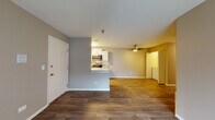 Located at 255 N Oakhurst Dr in Aurora, Illinois, this single-floor unit offers a practical and well-appointed layout designed for comfortable everyday living. The open-concept living and dining area greets residents upon entry, featuring warm wood-look plank flooring that extends throughout the main living spaces. Neutral gray and tan wall tones create a cohesive, move-in-ready aesthetic. A ceiling fan overhead adds both function and comfort to the living area.

The kitchen is efficiently designed with a galley-style layout, showcasing white cabinetry with modern hardware, granite-look countertops, a white subway tile backsplash, and a full suite of stainless steel appliances including a refrigerator, electric range, and over-the-range microwave. A convenient pass-through counter connects the kitchen to the main living space.

The bedrooms are carpeted for comfort and each include ceiling fans and ample natural light from windows with blinds. One bedroom features access to a walk-in closet area, providing useful storage.

The bathroom is well-finished with a granite-top vanity, framed mirror, stone-look tile flooring, and a full tub-shower combination with a curved curtain rod, complemented by brushed nickel fixtures and hardware throughout.