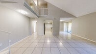Located at 13401 North 50th Street in Tampa, FL, this two-story, 3-bedroom, 5-bathroom home offers a well-designed layout across two floors. The main floor impresses with dramatic vaulted ceilings that create a striking sense of openness and volume in the combined living, dining, and kitchen area. Large format light-toned tile flooring runs throughout the main living spaces, enhancing the bright, airy ambiance. The kitchen features white cabinetry, granite countertops with a breakfast bar, stainless steel appliances, and a subway tile backsplash. Sliding glass doors lead from the living room to a private balcony, bringing in natural light and outdoor views. The upper floor houses the bedrooms, including a generously sized primary bedroom with light wood-style flooring, a ceiling fan, and a dedicated en-suite bathroom complete with a walk-in marble-surround shower. Additional bedrooms feature carpet flooring, ceiling fans, and windows with natural light. Five bathrooms in total serve the home, including tub-shower combinations in secondary baths. With five closets distributed throughout and two hallways connecting the layout, this home delivers both practicality and comfort in a functional Tampa residence.