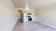 Located at 1601 N Oracle Rd in Tucson, Arizona, this efficiently designed studio unit offers a thoughtful layout across a single floor. The open living area is finished with light-toned luxury vinyl plank flooring that runs seamlessly throughout, lending a clean and cohesive aesthetic to the space. Crown molding adds a subtle architectural detail along the ceiling line.

The integrated kitchenette is positioned along one wall and features light wood cabinetry, a stainless steel range with an over-the-range microwave, a full-size refrigerator, and a single-basin sink — providing all essential cooking and prep functionality within a compact footprint. The living area benefits from a large sliding window that admits natural light and offers views of the surrounding outdoor common areas, complemented by a wall-mounted HVAC unit for year-round climate control.

A hallway connects the main living space to the full bathroom, which includes a tub/shower combination finished with large-format neutral ceramic tile surround and dark oil-rubbed bronze fixtures, delivering a polished contrast to the lighter tones found elsewhere. The unit's neutral color palette, updated finishes, and practical layout make it a functional and well-appointed space in the heart of Tucson.