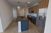 Located at 2380 Staples Rd in San Marcos, TX, this modern single-floor apartment offers 1,160 square feet of thoughtfully designed living space across 3 bedrooms and 2 bathrooms. The open-concept kitchen is a standout feature, showcasing a large center island with dark countertops and an integrated sink, complemented by globe pendant lighting. Two-toned cabinetry pairs charcoal lower cabinets with warm wood upper cabinets above a white tile backsplash, and stainless steel appliances complete the contemporary aesthetic. Light wood-tone flooring runs throughout the entire unit, creating a cohesive and airy feel. The primary bedroom spans 150 square feet and is served by a well-appointed bathroom featuring a dual-sink vanity with dark cabinetry, dark stone countertops, black-framed mirrors, and black hardware accents. A dedicated closet with double doors and built-in wire shelving provides ample storage. The secondary bedrooms are bright and generously sized, each featuring large windows with outdoor views and ceiling fans. Clean white walls, recessed lighting, and black hardware details throughout lend a crisp, modern character to this well-designed San Marcos residence.