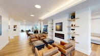 Located at 4301 Old William Penn Hwy in Monroeville, PA, this expansive single-floor amenity space offers a well-appointed and thoughtfully designed environment for relaxation, recreation, and fitness. The interior showcases a clean, contemporary aesthetic throughout, with light hardwood flooring, crisp white walls, and recessed and cove lighting that create a bright, welcoming ambiance.

The lounge area serves as the centerpiece of the space, featuring multiple seating arrangements with leather armchairs, plush sectional sofas, and accent furniture. A sleek linear fireplace is flanked by open shelving displaying curated décor, while artwork adds warmth and character. Natural light pours in through large windows, further enhancing the open, airy feel.

Adjacent areas transition seamlessly into a spacious game room equipped with a pool table and shuffleboard table, set against a backdrop of abundant natural light and lush potted plants. A kitchenette with stainless steel appliances is conveniently integrated nearby.

The fully equipped fitness center is divided into dedicated zones for cardio and strength training, featuring treadmills, ellipticals, cable machines, free weights, and stationary bikes. Full-length mirrors amplify the space, and rubber flooring provides safety and durability.

A resident mailbox area near the entrance offers practical functionality, rounding out this impressive, amenity-rich space.
