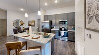 Located at 1971 Willow Loop Way in Knoxville, TN, this single-floor, 2-bedroom, 2-bathroom residence delivers a thoughtfully designed open-concept layout with modern finishes throughout. The kitchen and living room flow seamlessly together, anchored by a large granite-topped island with pendant lighting overhead. Gray shaker-style cabinetry, a subway tile backsplash, and a full suite of stainless steel appliances — including a French door refrigerator, electric range, and microwave — give the kitchen a polished, contemporary feel. Wood-style flooring extends through the main living areas, adding warmth and visual continuity. The living room offers generous natural light through a glass exterior door and windows framed by draping curtains, with a ceiling fan enhancing comfort. Both bedrooms feature plush carpet and ample closet space, with the primary bedroom including its own dedicated closet and direct access to a private bathroom. A walk-in closet with wire shelving provides practical storage. The bathrooms are clean and functional, with one featuring a full soaking tub and shower combination. A pantry and hallway round out the floorplan, contributing to an organized and efficient use of space throughout this well-appointed Knoxville residence.