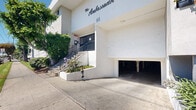 Located at 111 N Eucalyptus Ave in Inglewood, California, this exterior space offers a comprehensive street-level view of a established residential corridor under the clear Southern California sky. The immediate surroundings feature well-kept green lawns running along the sidewalks, complemented by a canopy of mature shade trees that line the boulevard and provide ample greenery throughout the neighborhood.

The building itself presents a clean, modern stucco facade in a neutral gray-and-tan color scheme, rising multiple stories with evenly spaced windows. Ground-level covered parking is accessible from the street, framed by neatly trimmed landscaping with shrubs and flowering plants that enhance the building's curb appeal.

The surrounding streetscape along N Eucalyptus Ave reflects a dense, mixed residential neighborhood, with a variety of multi-story buildings of differing architectural styles — from Spanish-influenced rooflines to contemporary flat-top designs — visible in close proximity. Wide, paved sidewalks with red curbing and accessible crosswalks serve the area. On-street parking is available along the corridor. The neighborhood enjoys excellent visibility at a prominent corner intersection, offering convenient access and strong street presence within this active Inglewood community.