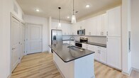 Located at 451 W Blount Ave in Knoxville, TN, this thoughtfully designed one-bedroom, one-bathroom unit offers a clean, modern aesthetic throughout. The open-concept kitchen and living area serves as the heart of the home, anchored by a large center island with a dark quartz countertop, an undermount sink, and elegant pendant lighting overhead. White shaker-style cabinetry lines the walls, complemented by a classic subway tile backsplash and a full suite of stainless steel appliances, including a French door refrigerator, electric range, and built-in microwave. Light wood-look flooring flows throughout the main living areas, enhancing the bright and airy feel. The living area extends to a private balcony through a glass-panel door, allowing for generous natural light and outdoor views. The bedroom features plush carpeting, a ceiling fan, and multiple windows that bring in abundant daylight. A walk-in closet with wire shelving provides practical storage. The bathroom offers a clean, contemporary finish with a dark-topped double vanity, a tiled soaking tub, and wood-look tile flooring. Additional conveniences include a dedicated laundry area and a utility room, rounding out this well-appointed and efficiently designed residence.