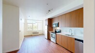 Located at 3750 South River Parkway in Portland, Oregon, this one-bedroom, one-bathroom unit offers a well-designed, efficiently laid-out living space with modern finishes throughout. The open-concept kitchen and living area forms the heart of the unit, featuring warm wood-grain flat-front cabinetry extending floor to ceiling, stainless steel appliances including an electric range, over-the-range microwave, refrigerator, and dishwasher, complemented by clean white countertops and a white tile backsplash. Rich hardwood-style flooring runs continuously throughout the space, adding warmth and visual cohesion. A large window at the end of the living area fills the room with natural light and provides a view of surrounding greenery. The bedroom is a comfortable, well-proportioned space with its own window framing a scenic view of the river and lush tree line — a standout feature of the unit. Two closets provide practical storage solutions. The bathroom continues the cohesive design aesthetic with matching wood-grain cabinetry, a large vanity mirror, white countertop with an undermount sink, and a clean, functional layout. The unit's consistent use of warm tones and modern finishes creates a bright, contemporary living environment.