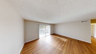 Located at 425-455 E Washington Ave in Escondido, California, this 2-bedroom, 2-bathroom unit offers a well-organized single-floor layout designed for comfortable everyday living. Warm hardwood-style flooring runs throughout the home, providing a cohesive and inviting look across all rooms.

The living room is a bright, open space anchored by a sliding glass door with vertical blinds that leads to a private balcony, allowing natural light to pour in and illuminate the room. A textured ceiling adds a classic touch to the space.

The kitchen is efficiently laid out in a U-shape configuration, featuring white shaker-style cabinetry, light countertops, a stainless steel sink, and white appliances including a range, dishwasher, and refrigerator. A ceiling light fixture provides functional overhead illumination, and the hardwood-style flooring continues seamlessly from the adjacent living area.

The spacious primary bedroom includes a mirrored sliding closet, crown molding, a textured ceiling, and a window with outdoor views of surrounding greenery. The second bedroom is also generously sized, featuring a large window that brings in ample natural light. Both bathrooms include shower enclosures. A connecting hallway ties the layout together, completing this functional and comfortable home.
