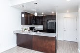 Located at 1999 W North Temple Street in Salt Lake City, Utah, this one-bedroom, one-bathroom unit offers a well-designed single-floor layout. The open-concept kitchen serves as the heart of the home, featuring rich dark espresso cabinetry, granite countertops, a peninsula with a double stainless steel sink, pendant lighting, and a full suite of black appliances including a refrigerator, range, and built-in microwave. The kitchen flows seamlessly into the living area, which is brightened by a window and a ceiling fan, creating an airy, connected feel. Light wood-style flooring runs throughout the main living areas, adding warmth and continuity. The bedroom is a comfortable retreat, carpeted for added comfort and equipped with a ceiling fan, a natural light-providing window, and a sliding-door closet offering ample storage. The bathroom is clean and well-appointed, with a granite-topped vanity with dark cabinetry, a large mirror, a tub-shower combo with tiled surround, and wood-style flooring. A hallway connects the rooms efficiently, completing this thoughtfully laid-out home that balances functionality with modern, consistent design elements throughout.