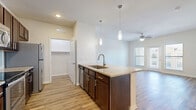 Located in Richmond, TX, this well-appointed 3-bedroom, 3-bathroom residence offers a thoughtfully designed single-level layout. The open-concept kitchen and living area serves as the heart of the home, anchored by a granite-topped island with a built-in sink and pendant lighting overhead. Rich dark-wood cabinetry, a mosaic tile backsplash, and a full suite of stainless steel appliances — including a refrigerator, range, and microwave — complete the kitchen. Wood-style flooring flows seamlessly throughout the entire residence, lending warmth and visual continuity. The living room is bright and airy, benefiting from natural light through a sliding glass door and a ceiling fan for added comfort. Each of the three bedrooms offers a clean, neutral palette with ample space, while one bedroom features direct outdoor access. The primary bedroom is served by a spacious en-suite bathroom with a dual-sink vanity, granite counters, dark cabinetry, and a tiled soaking tub and shower combination. Additional bathrooms mirror the same quality finishes. The residence also includes two closets and a dedicated laundry area, providing practical storage and convenience throughout.