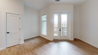 Located at 1711 Commonwealth Ave in Charlotte's vibrant Plaza Midwood neighborhood, this thoughtfully designed one-bedroom, one-bathroom residence offers a clean, modern aesthetic throughout. Light wood-look flooring flows continuously through the space, complementing the crisp white walls and black accent hardware found in every room.

The open-concept kitchen and dining area serves as the heart of the home, showcasing a striking two-tone cabinet design with white upper cabinetry and warm wood-toned lower cabinets, a herringbone tile backsplash, and a large central island topped with elegant white marble-veined quartz. Stainless steel appliances and a matte black faucet complete the chef-ready setup. Dramatic pendant lights hang above the island, adding a bold design statement. French doors open from the living area to a private patio with a modern slatted railing, offering open views of the surrounding Charlotte skyline.

The bedroom features high ceilings, a ceiling fan, and a horizontal band of black-framed windows that bring in natural light while maintaining privacy. Three closets, including a walk-in with wire shelving, provide generous storage. The bathroom includes a tub-shower combination with white tile surround and matte black fixtures. Recessed lighting and thoughtful finishes make this a polished, move-in-ready residence.