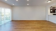 This single-floor residence offers a well-organized, open-concept layout designed for comfortable everyday living. Warm wood-look flooring flows consistently throughout the main living areas and bedrooms, creating a cohesive aesthetic across the space.

The living area is generously proportioned, featuring recessed lighting and clean white walls that contribute to a bright, airy atmosphere. It connects directly to the kitchen via a white peninsula counter, which serves as both a functional workspace and a natural divider between the two areas. The kitchen is well-appointed with rich, dark espresso-toned cabinetry extending to the ceiling for ample storage, white countertops, a tile backsplash, and a full suite of stainless steel appliances including a side-by-side refrigerator, electric range, and built-in microwave. Pendant lighting above the peninsula adds a refined finishing touch.

The bedrooms are comfortably sized, each featuring wood-look flooring, neutral walls, and windows fitted with blinds that allow for natural light while maintaining privacy. Two full bathrooms serve the residence, each featuring dark vanity cabinetry with white countertops, a large mirror, and a tub-shower combination with clean white surrounds.