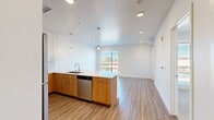 Located at 1298 Lamar St in Lakewood, Colorado, this well-appointed one-bedroom, one-bathroom unit offers a thoughtfully designed layout with modern finishes throughout. The open-concept kitchen and living area serves as the heart of the home, featuring warm wood-toned lower cabinetry paired with crisp white upper cabinets, a sleek quartz countertop peninsula, subway tile backsplash, and a full suite of stainless steel appliances including a refrigerator, range, microwave, and dishwasher. Pendant lighting adds a stylish touch above the peninsula, while recessed lighting illuminates the entire space. Wood-look plank flooring runs throughout the main living areas and hallway, lending a clean, contemporary aesthetic. The living area is bathed in natural light through large windows with views of the surrounding neighborhood. The bedroom offers a comfortable, carpeted retreat with a ceiling fan, a generous closet, and its own window with outdoor views. The full bathroom is finished with light tile flooring, a wood-toned vanity with quartz countertop, and a tiled tub-shower combination. A dedicated closet provides additional storage. Clean white walls and a neutral palette throughout create a bright, cohesive ambiance well-suited for modern living.