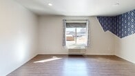 Located at 516 NW 8th St in Oklahoma City, OK, this one-bedroom, two-bathroom unit delivers a thoughtfully designed layout within a compact footprint. The open-plan living, dining, and kitchen area flows efficiently, maximizing every square foot with wood-look plank flooring that extends throughout the space, lending warmth and visual continuity.

The bedroom is a standout feature, showcasing a striking geometric blue-and-white diamond-patterned accent wall that adds bold personality to the room. A window with decorative curtains allows natural light to filter in while offering views of the surrounding cityscape. An in-unit PTAC climate control unit ensures year-round comfort.

A separate area of the unit reveals a painted brick accent wall in a cool slate tone, providing an urban, loft-inspired aesthetic that contrasts beautifully with the clean white ceilings fitted with recessed lighting.

The two bathrooms are well-appointed, with at least one featuring a frameless glass walk-in shower adorned with large-format marble-look tile, brushed nickel hardware, and a built-in shelf — a sleek, modern finish that elevates the overall design. Two closets provide practical storage solutions.

The layout, as seen in the dollhouse view, makes efficient use of space with a barn-style sliding door adding an industrial design touch. This unit offers a stylish urban living experience in the heart of Oklahoma City.