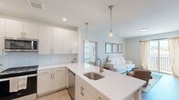 This thoughtfully designed 2-bedroom, 2-bathroom residence in Howell, NJ offers a clean, modern aesthetic throughout its well-utilized single-floor layout. The open-concept kitchen flows seamlessly into the living area, creating a bright and cohesive living space. The kitchen is outfitted with white flat-panel cabinetry, a light blue subway tile backsplash, stainless steel appliances including a gas range, built-in microwave, and French door refrigerator, along with a peninsula featuring a quartz countertop and stainless steel sink illuminated by globe pendant lights. The living room benefits from natural light through a sliding glass door that opens to a private balcony, complemented by light wood-style flooring that runs throughout. The primary bedroom is a comfortable, well-proportioned retreat with a dedicated closet and access to its own bathroom. The second bedroom features a window with views and ample natural light. Both bathrooms are finished with light wood vanities, white quartz countertops, large mirrors, and wood-look or tile flooring — one featuring a glass-enclosed shower. Two closets provide practical storage. The overall palette of white walls, light floors, and brushed nickel fixtures creates a fresh, contemporary ambiance throughout.