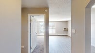 Located at 4327 N Chestnut St in Colorado Springs, Colorado, this single-floor unit offers a clean, functional layout designed for comfortable everyday living. The open living area features light-toned luxury vinyl plank flooring that runs seamlessly throughout, complemented by neutral gray walls and a textured ceiling. Natural light filters in through multiple windows fitted with blinds, creating a bright and welcoming atmosphere. A wall-mounted HVAC unit and baseboard heating ensure year-round climate control.

The kitchen is efficiently designed with white shaker-style cabinetry, granite-look countertops, a single-basin sink with a modern faucet, and stainless steel appliances including a range and refrigerator. An arched passageway adds a subtle architectural detail connecting the kitchen to the rest of the unit.

The carpeted bedroom provides a softer, cozier feel, complete with a ceiling fan with light fixture and a window that brings in natural light. Baseboard heating is also present in this room for added comfort.

The bathroom is finished in a clean, all-white palette, featuring a full tub-shower combination with tiled surround and chrome fixtures. Throughout the unit, the consistent use of neutral tones and updated finishes creates a cohesive, move-in-ready environment.