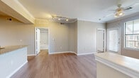This single-floor unit offers a thoughtfully designed layout that maximizes functionality within a compact footprint. The open-concept living and kitchen area forms the heart of the space, where warm wood-style flooring flows seamlessly underfoot. The living room features crown molding, a ceiling fan, and a large window with an exterior door that allows abundant natural light and outdoor views of the surrounding grounds.

The kitchen is well-equipped with dark espresso cabinetry, granite countertops, a tile backsplash, stainless steel appliances including a refrigerator and microwave, and a built-in electric range. A peninsula with a granite countertop and undermount sink provides additional workspace and serves as a natural divider between the kitchen and living areas. Track lighting above adds focused illumination throughout.

The bedroom is carpeted for comfort, features a ceiling fan, and includes a window with outdoor views, providing a quiet retreat. A walk-in closet offers practical storage. The bathroom includes a full tub-shower combination with tile surround, wood-style flooring, a granite-topped vanity, and built-in open shelving for additional storage.