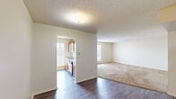 This single-floor residence in Baton Rouge, Louisiana offers a well-organized layout with two bedrooms, two bathrooms, and a combined kitchen and living area. The entryway features light wood-look flooring that extends through the main living spaces, creating a clean and cohesive aesthetic. The galley-style kitchen is lined with warm wood cabinetry on both sides, light countertops, and white appliances including a range, refrigerator, and dishwasher. A window at the end of the kitchen brings in natural light and overlooks the exterior. The adjacent living room is generously sized, featuring plush carpeting, a textured ceiling, and a window that allows additional natural light. Both bedrooms are carpeted and include windows with exterior views, providing a comfortable and bright atmosphere. The primary bedroom offers ample space. The two bathrooms are finished with wood-look flooring, vanities with light countertops, and full tub-and-shower combinations. One bathroom features tile surround and built-in shelving for added storage. A dedicated utility closet with built-in shelving and laundry hookups adds practical functionality to the home. Throughout, neutral tones and clean finishes create a move-in ready environment.