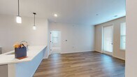 This single-floor residence features a thoughtfully designed open-concept layout that seamlessly connects the kitchen and living areas. The kitchen is appointed with white shaker-style upper cabinets, sage-green lower cabinetry, a white quartz peninsula countertop, subway tile backsplash, stainless steel appliances including a refrigerator, range, and microwave, and pendant lighting overhead. An adjacent in-unit laundry closet adds everyday convenience. Wood-look plank flooring runs throughout the kitchen and living spaces, lending a warm, contemporary feel.

The living area is bright and open, benefiting from natural light through multiple windows fitted with horizontal blinds, and includes access to an exterior door. Two bedrooms are finished with plush wall-to-wall carpeting and multiple windows that invite ample natural light into each room.

The primary bathroom offers a dual-sink vanity with sage-green shaker cabinets, white quartz countertops, black hardware accents, and wood-look flooring. The secondary bathroom features a single-sink vanity with matching cabinetry and a full tub-shower combination. Neutral wall tones and clean finishes throughout the unit contribute to a cohesive, modern aesthetic.