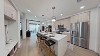 This well-designed 630-square-foot, one-bedroom, one-bathroom apartment offers a thoughtful single-floor layout that maximizes every square foot. Light wood flooring flows consistently throughout, creating a cohesive and airy aesthetic across all rooms.

The open-concept living room connects directly to a private balcony via floor-to-ceiling sliding glass doors, filling the space with natural light and outdoor views. The kitchen is a standout feature, equipped with light wood cabinetry extending to the ceiling, a gray tile backsplash, stainless steel appliances including a French door refrigerator and over-the-range microwave, and a white quartz waterfall island with bar seating and an undermount sink — ideal for both cooking and casual dining.

The 140-square-foot primary bedroom features a tray ceiling, ceiling fan, and a large window with outdoor views. The bathroom offers a glass-enclosed walk-in shower, white quartz vanity, gray cabinetry, and large-format tile flooring. It connects directly to a dedicated walk-in closet outfitted with adjustable shelving, hanging rods, and ample storage. A hallway completes the layout, providing smooth circulation throughout the unit.