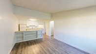 Located at 4306 Royal Glen Dr NE in Comstock Park, Michigan, this one-bedroom, one-bathroom unit offers a practical and well-organized single-floor layout. The open-concept kitchen and living area serves as the heart of the space, featuring wood-look luxury vinyl flooring, white shaker-style cabinetry, granite-look countertops, a stainless steel sink, and white appliances including an electric range and refrigerator. A peninsula with open shelving below provides additional storage and a natural division between the kitchen and living area. The living room benefits from a large window that allows natural light to fill the space and offers views of the surrounding greenery. The bedroom is carpeted for comfort, includes a ceiling fan with light fixture, and features its own window with outdoor views. Two closets provide generous storage throughout the unit. The full bathroom is finished with wood-look flooring, a white vanity with a large mirror, and a shower-tub combination. A dedicated utility room houses the water heater and additional mechanical systems. The interior is finished with textured ceilings and neutral walls throughout, creating a clean and functional living environment.
