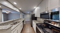 This single-floor, 2-bedroom, 2-bathroom residence in Woodbridge presents a clean black-and-white color scheme complemented by warm neutral tones throughout. The galley-style kitchen is a standout feature, showcasing white shaker cabinetry with sleek hardware, granite countertops, a stainless steel sink, and a full suite of stainless steel appliances including an electric range, over-the-range microwave, refrigerator, and dishwasher. Wood-style plank flooring runs through the kitchen and main living areas, adding warmth and durability.

The living area is bright and open, featuring a ceiling fan and a sliding glass door that invites natural light and provides outdoor views. Both bedrooms are comfortably sized, carpeted for comfort, and each includes a ceiling fan and a window with blinds that allow natural light.

Both bathrooms maintain the home's consistent aesthetic with white cabinetry, granite-topped vanities, and wood-style flooring. One bathroom includes a soaking tub with shower, while the other features a dedicated shower area. The overall design is cohesive and modern, emphasizing clean lines, neutral tones, and functional finishes throughout.